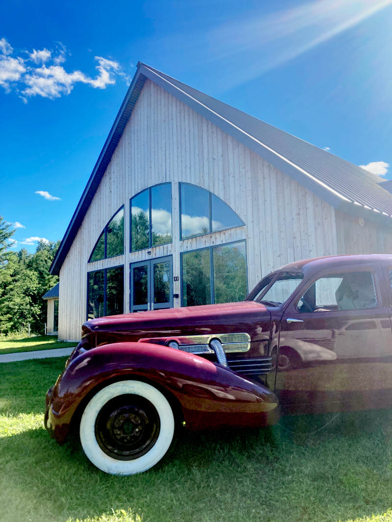 Image of classic red Cord 1937 automobile in front of vineyard entrance 